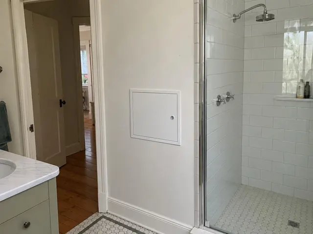 Bathroom wall with a neat white access panel beside a tiled shower and vanity in Mortdale